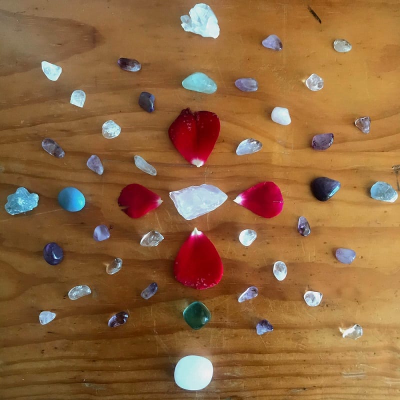 a crystal grid with rose petals and quartz crystals