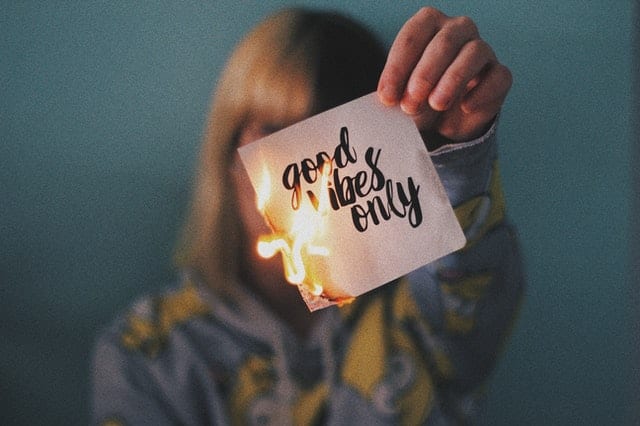 person burning a note that says "good vibes only"